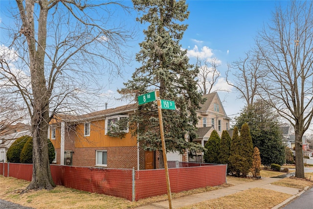 view of side of home with a fenced front yard and brick siding