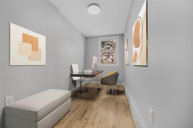 home office featuring a baseboard radiator, light wood-style flooring, and baseboards