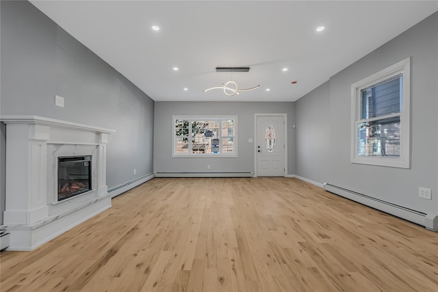 unfurnished living room featuring a baseboard heating unit, wood finished floors, a baseboard radiator, and a fireplace