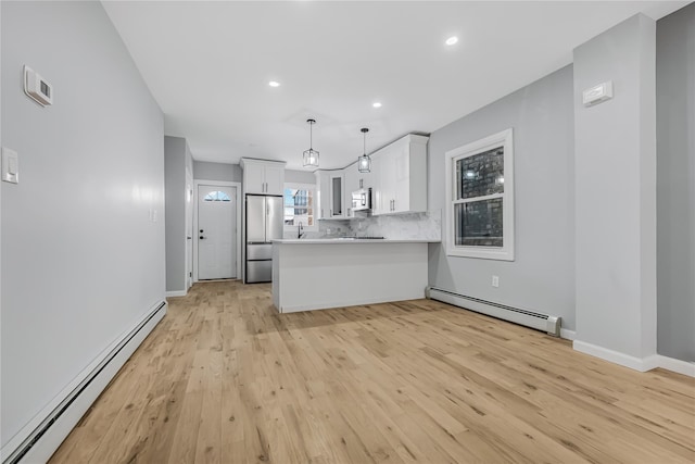 kitchen with a baseboard heating unit, stainless steel appliances, a peninsula, and tasteful backsplash