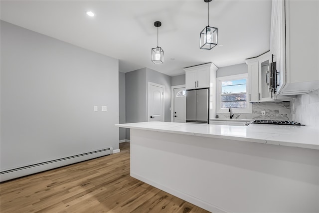 kitchen with tasteful backsplash, white cabinets, a baseboard radiator, a peninsula, and stainless steel appliances