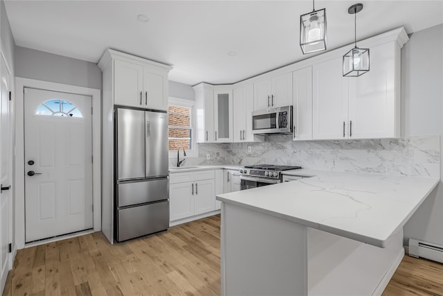 kitchen featuring a peninsula, a baseboard radiator, white cabinetry, and stainless steel appliances