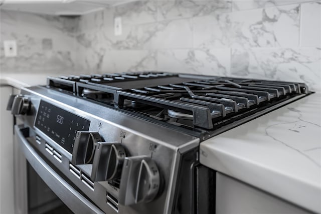 details featuring tasteful backsplash and stainless steel range with gas cooktop