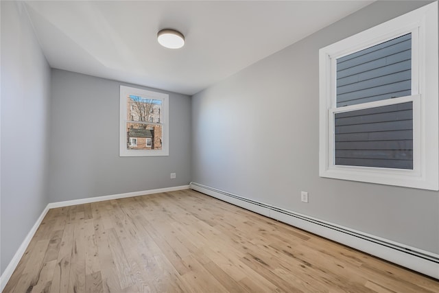 empty room featuring baseboards, baseboard heating, and wood finished floors