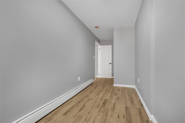 empty room featuring light wood finished floors, baseboards, and baseboard heating