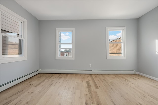 spare room with light wood-style floors, a baseboard radiator, and baseboards