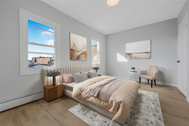 bedroom featuring light wood-type flooring, a baseboard radiator, and baseboards