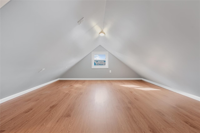 additional living space featuring light wood-style floors, lofted ceiling, and baseboards