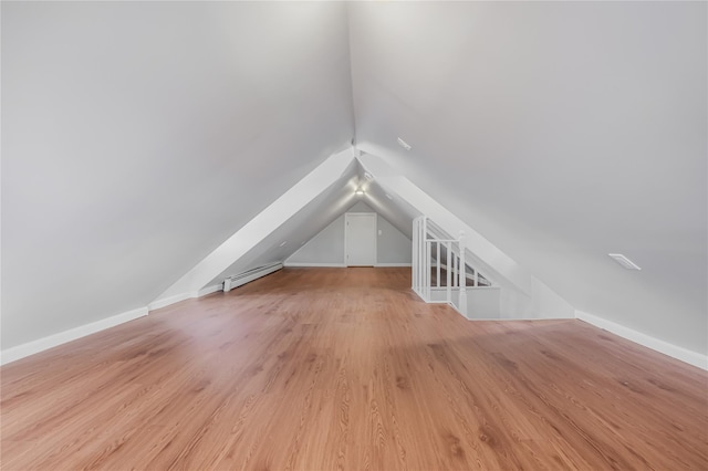 bonus room with lofted ceiling, baseboard heating, light wood-style flooring, and baseboards