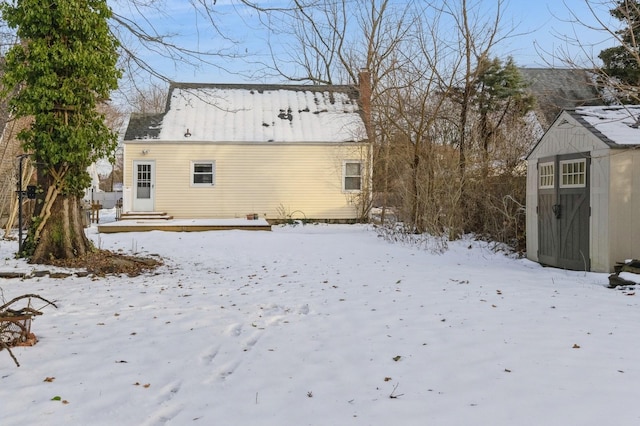 snow covered property with a storage unit and an outdoor structure