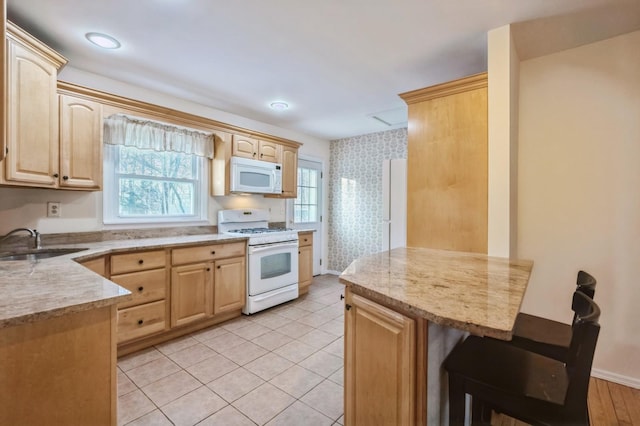 kitchen featuring a sink, white appliances, light brown cabinets, and wallpapered walls