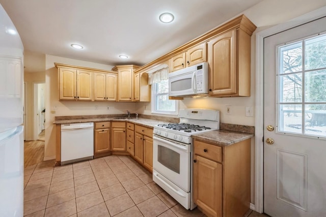 kitchen with light tile patterned flooring, recessed lighting, white appliances, a sink, and light brown cabinetry