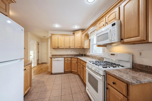 kitchen with light tile patterned floors, recessed lighting, light brown cabinets, a sink, and white appliances