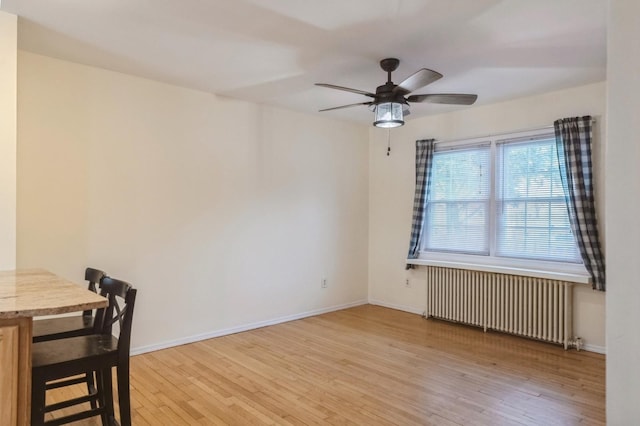 dining area featuring baseboards, light wood finished floors, and radiator heating unit