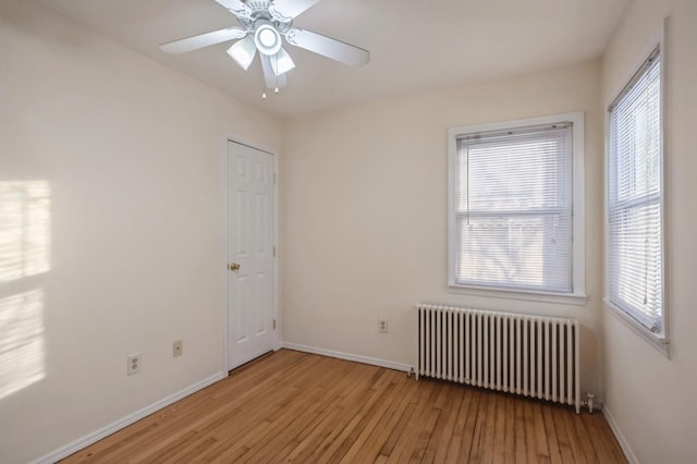 unfurnished room featuring ceiling fan, radiator heating unit, baseboards, and wood-type flooring