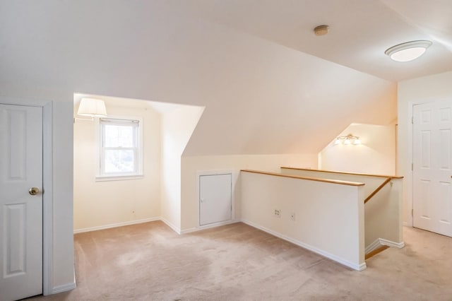 additional living space with lofted ceiling, light colored carpet, and baseboards