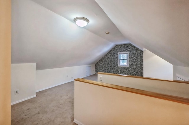 additional living space featuring lofted ceiling, light colored carpet, and baseboards