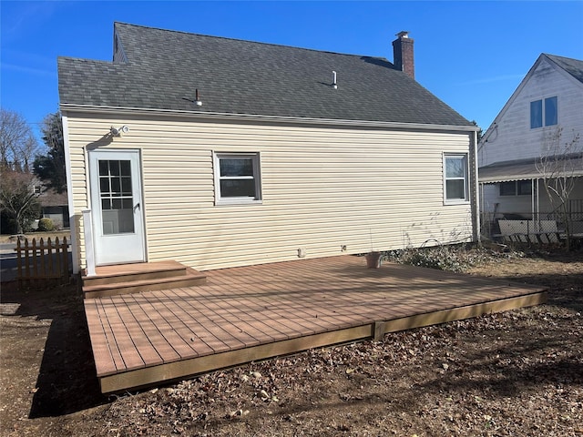 back of property featuring roof with shingles, a chimney, entry steps, fence, and a deck