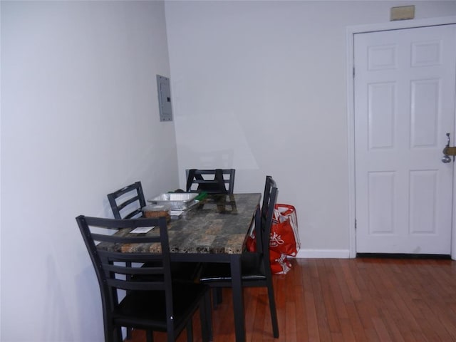 dining area with wood finished floors, electric panel, and baseboards