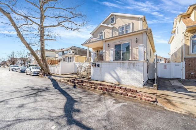 view of front of home featuring stairway, a gate, fence, and stucco siding