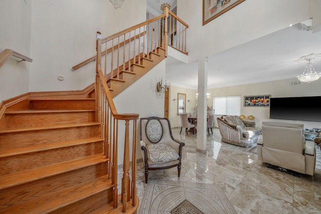 staircase featuring visible vents, ornamental molding, marble finish floor, an inviting chandelier, and a high ceiling