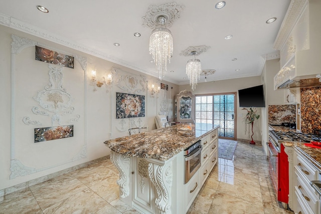 kitchen featuring a kitchen island, appliances with stainless steel finishes, ornamental molding, dark stone countertops, and premium range hood