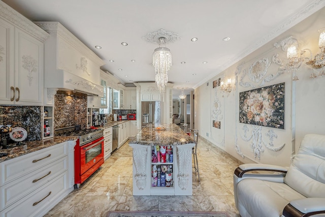 kitchen with a chandelier, stainless steel appliances, dark stone countertops, a kitchen bar, and crown molding