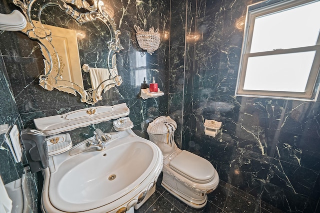 half bath featuring a sink, toilet, and tile walls