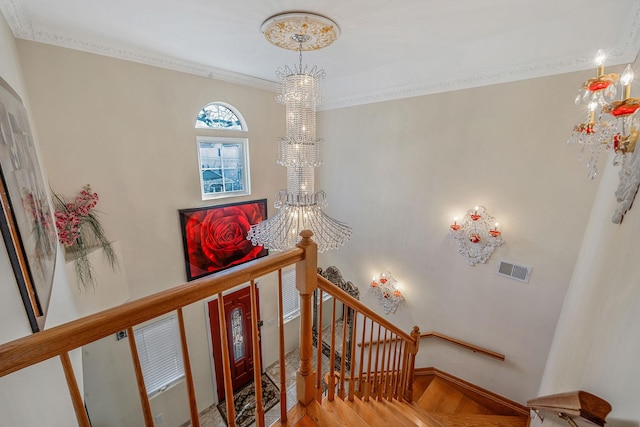 stairway with visible vents, ornamental molding, a chandelier, baseboards, and parquet flooring