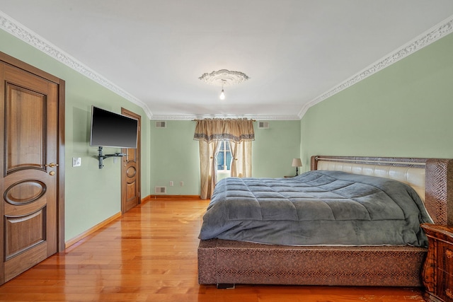 bedroom featuring visible vents, ornamental molding, light wood-style flooring, and baseboards