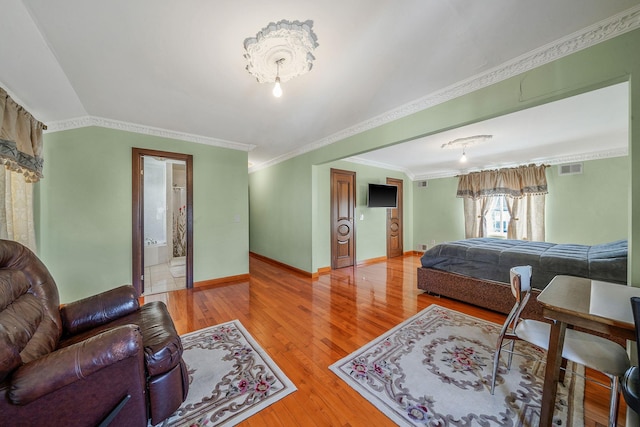 bedroom with lofted ceiling, hardwood / wood-style flooring, visible vents, baseboards, and crown molding