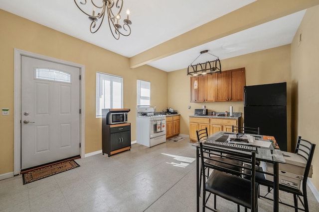 kitchen featuring freestanding refrigerator, baseboards, beamed ceiling, and white gas stove