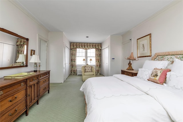 bedroom with ornamental molding, multiple closets, and light colored carpet