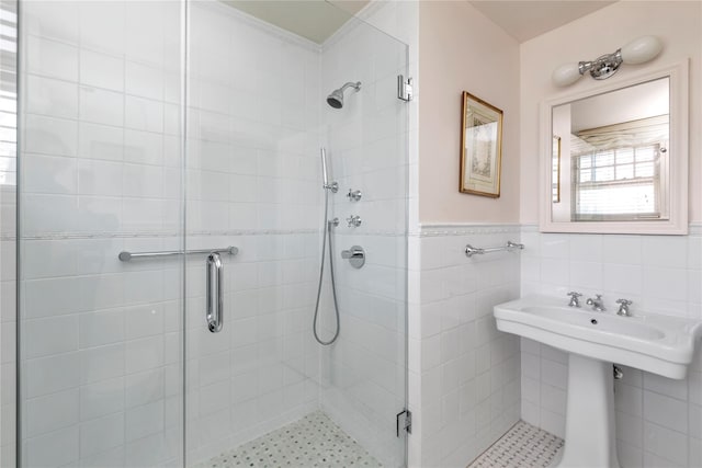 bathroom featuring a stall shower, a wainscoted wall, and tile walls