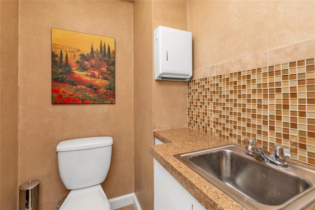 bathroom featuring tasteful backsplash, baseboards, vanity, and toilet