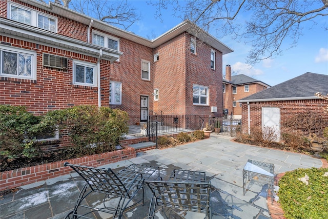 rear view of property with brick siding, a patio area, and fence