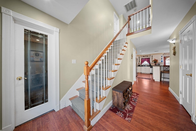 stairs with baseboards, visible vents, and wood finished floors