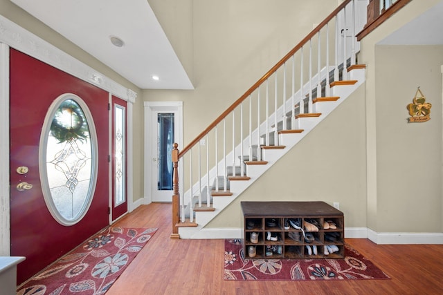 entrance foyer with a high ceiling, stairway, wood finished floors, and baseboards