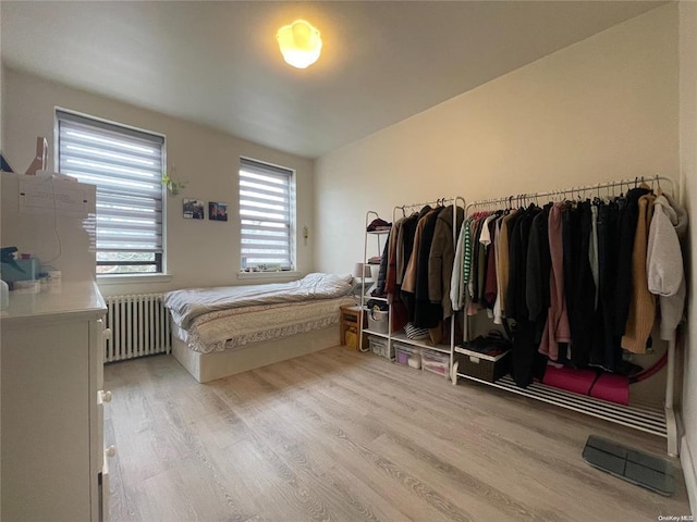 bedroom with radiator heating unit and light wood-type flooring