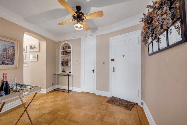 entryway with arched walkways, a ceiling fan, and baseboards