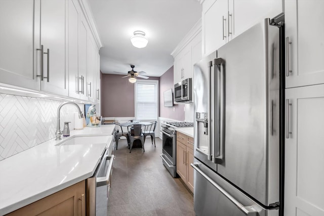 kitchen featuring decorative backsplash, ceiling fan, appliances with stainless steel finishes, light countertops, and a sink