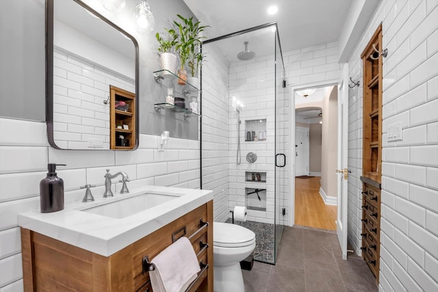 full bath featuring tile walls, toilet, a stall shower, vanity, and tile patterned flooring