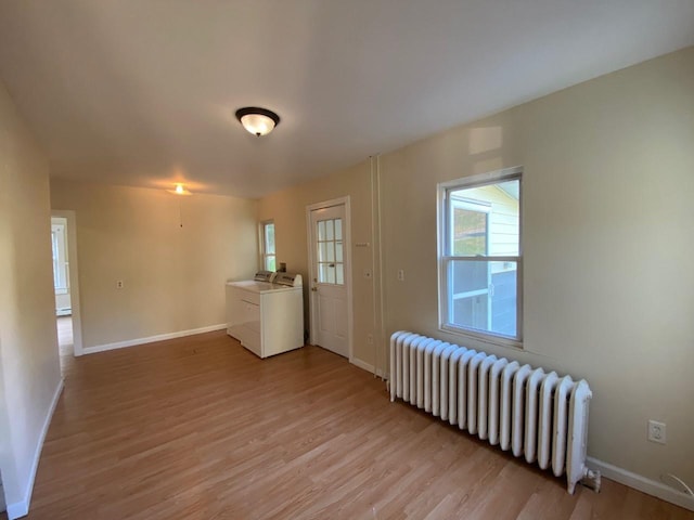 interior space featuring radiator, light wood finished floors, baseboards, and washer and dryer