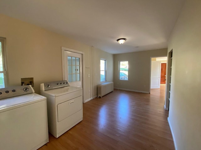 washroom with laundry area, baseboards, light wood-style floors, radiator, and washer and clothes dryer