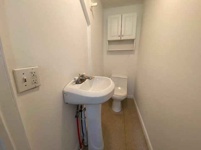 bathroom featuring a sink, tile patterned flooring, toilet, and baseboards