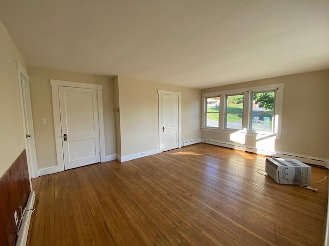 interior space with a baseboard heating unit, baseboards, and hardwood / wood-style floors