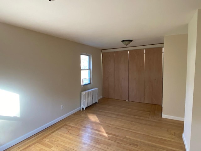 unfurnished bedroom featuring radiator, light wood finished floors, and baseboards