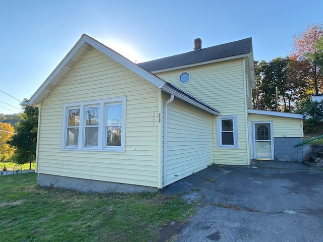 rear view of house with a patio area, a chimney, and a lawn