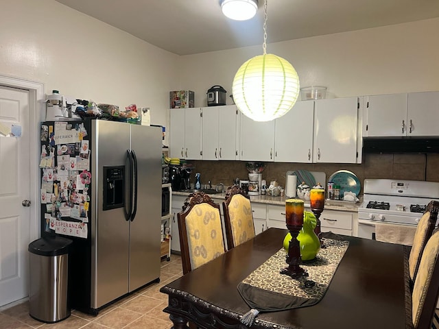 kitchen with under cabinet range hood, white gas range oven, stainless steel fridge, light tile patterned floors, and decorative backsplash