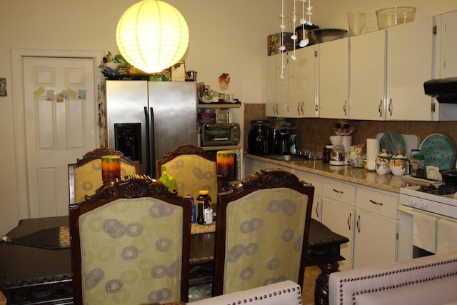 kitchen with white cabinets, stainless steel fridge, and under cabinet range hood